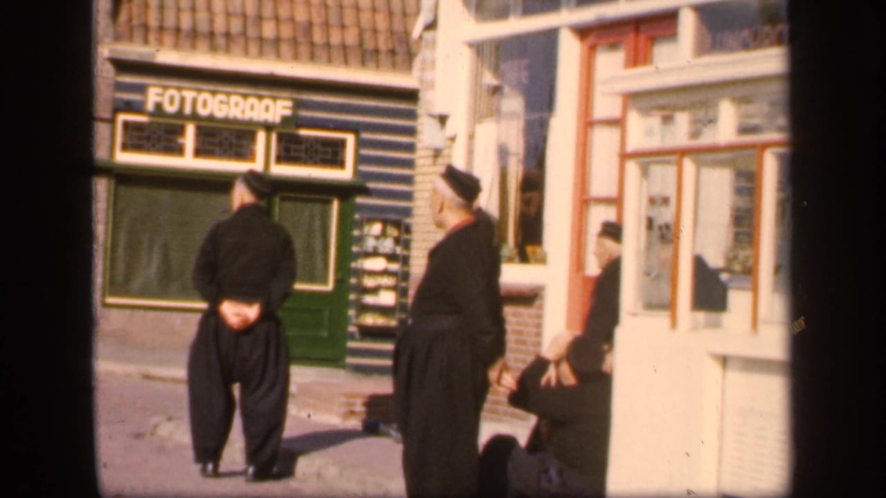 Men in dark clothing stand near a shopfront with a readable FOTOGRAAF sign.
