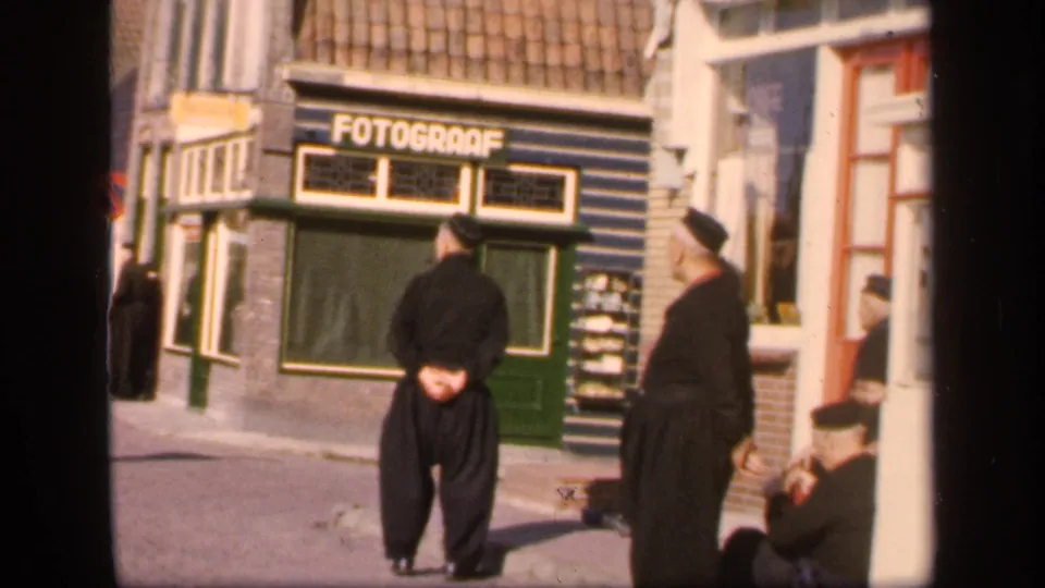 Street scene from the supplied 1949 Ireland metadata, showing two men in dark dress near a green FOTOGRAAF shopfront.