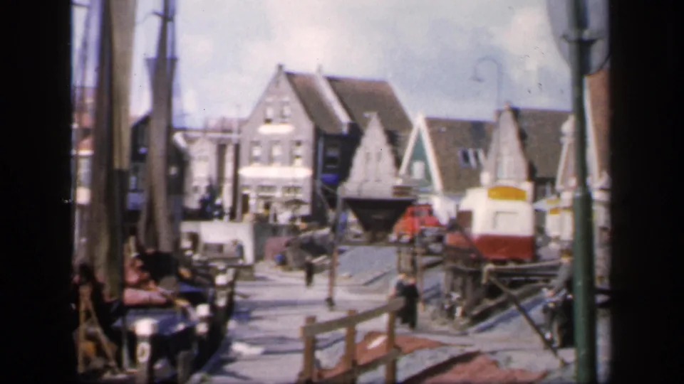 Wider 8mm frame from the 1949 Ireland-labeled clip shows waterfront street details, gabled facades, posts, railings, and a small rail vehicle.