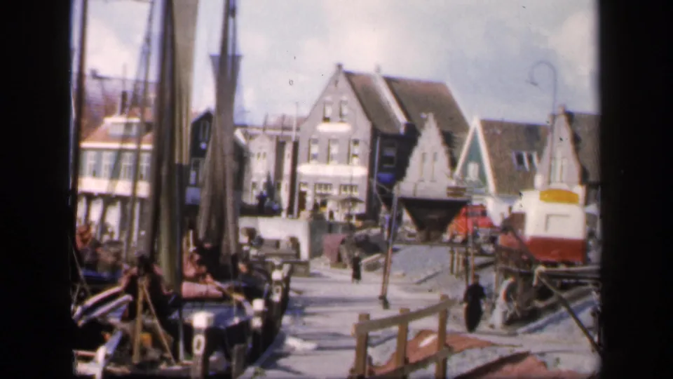In the final 1949 Ireland-labeled frame, a pedestrian crosses near waterfront railings, gabled buildings, posts, and a small rail vehicle.