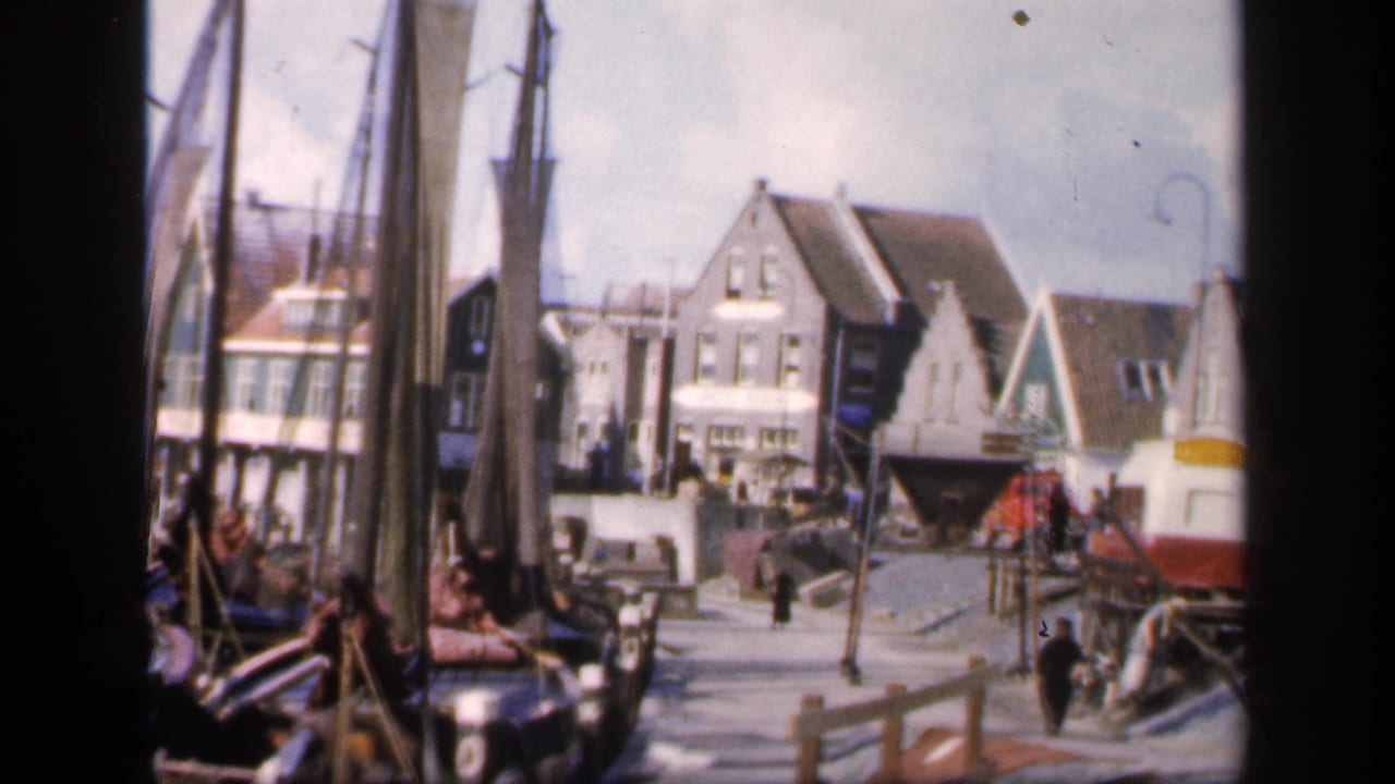 Fishing boats and masts beside a quay with waterfront buildings in the background.