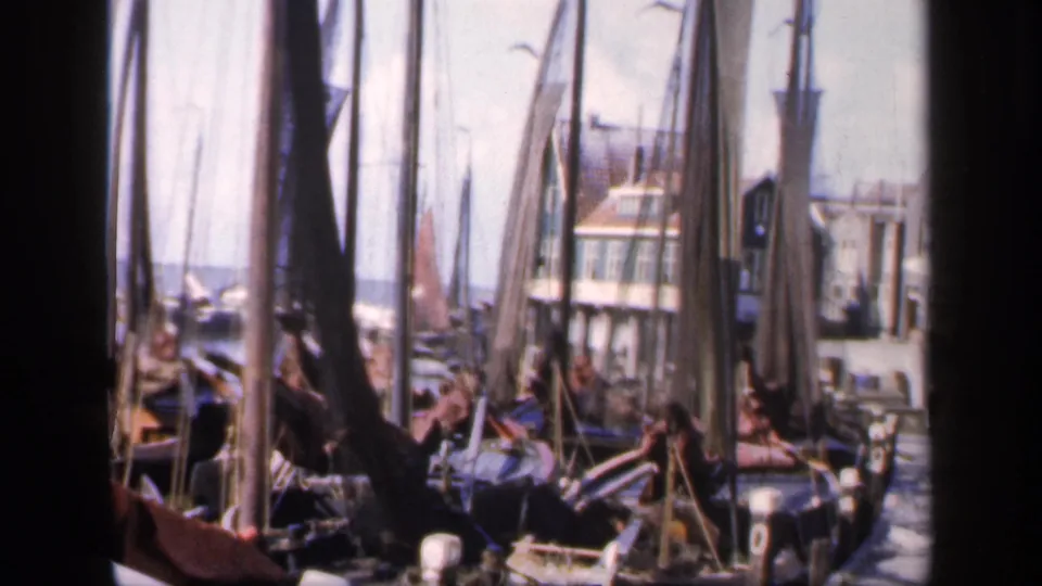 1949 Ireland harbor frame with clustered masts, boats, rigging, a quay, and people near gabled waterfront buildings.