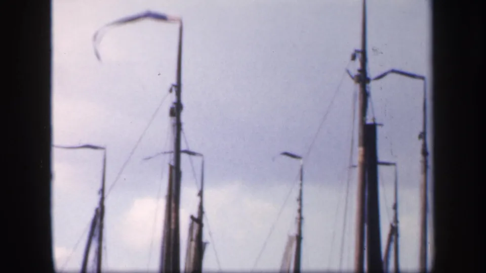 1949 Ireland harbor frame with tall sailboat masts, rigging lines, furled sails, and simple lamp posts in soft 8mm color.