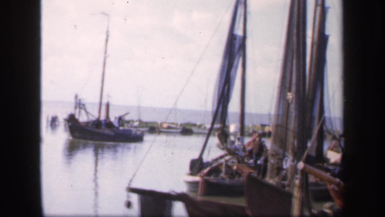 Small boat on still water with moored sailboats at the right edge.