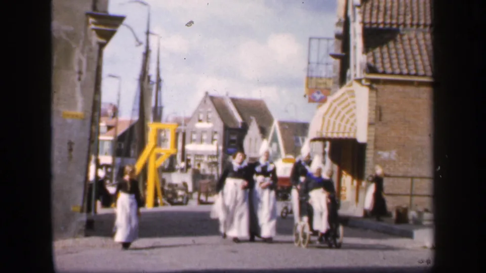 The group of women in traditional Irish attire continues along a 1949 town street with bicycles, pedestrians, and bridge machinery visible.