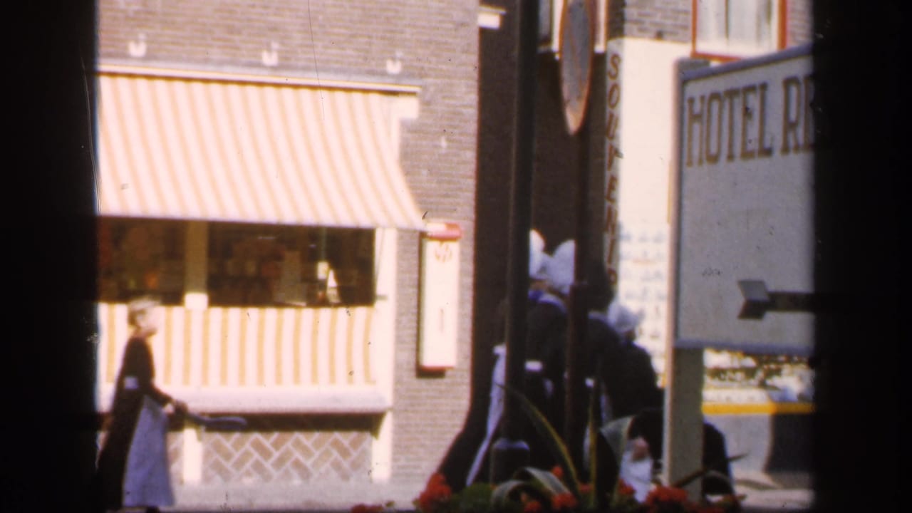 Pedestrian near a striped shop awning and partial hotel sign on a town street.