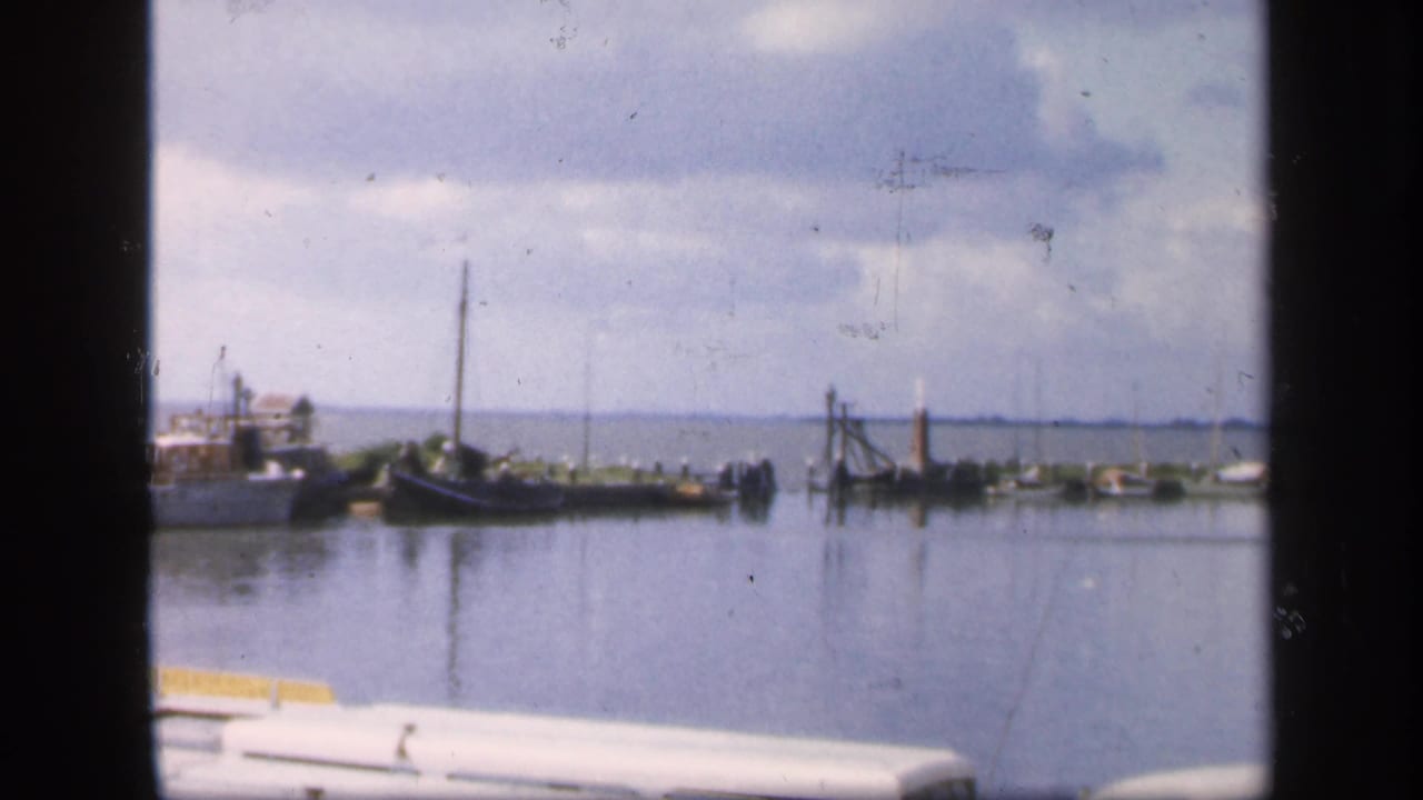 Boats moored in a calm harbor under a cloudy sky.