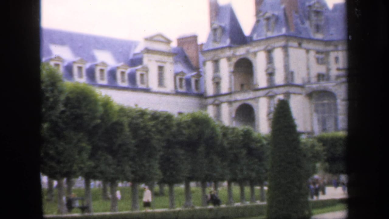 Ornate stone building and formal garden viewed through dark vertical framing.