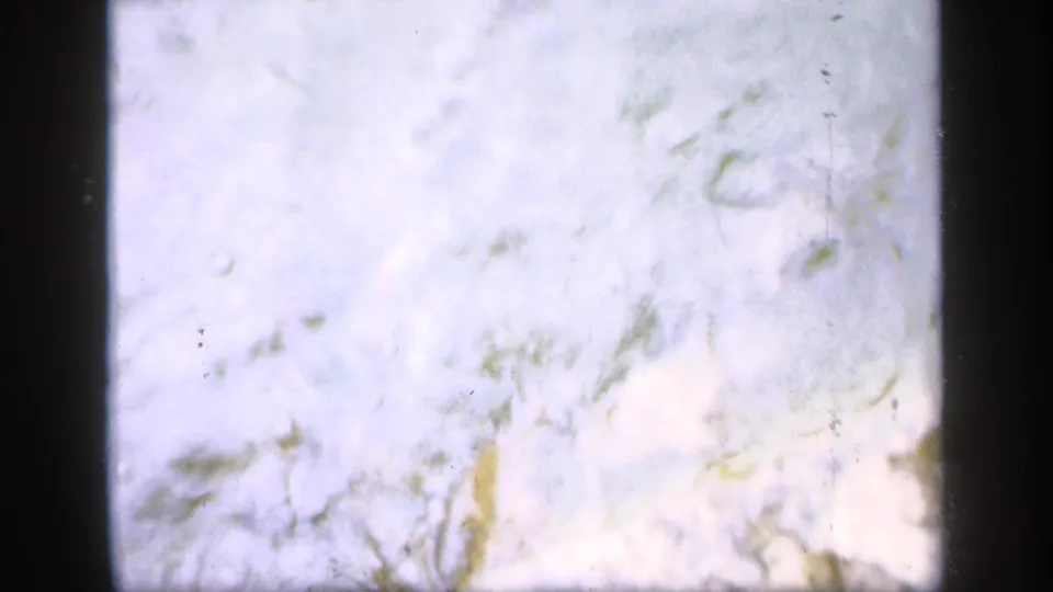 Soft 8mm frame from Ireland 1949 showing pale pond water, faint debris, and dark film borders.