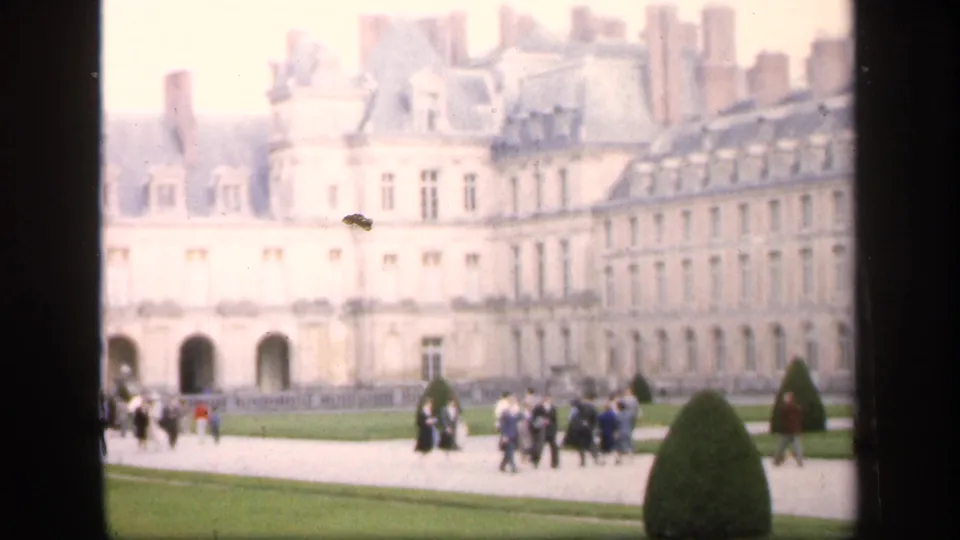 1949 Ireland travel-frame showing visitors in a manicured garden near a large ornate building with rows of windows and chimneys.
