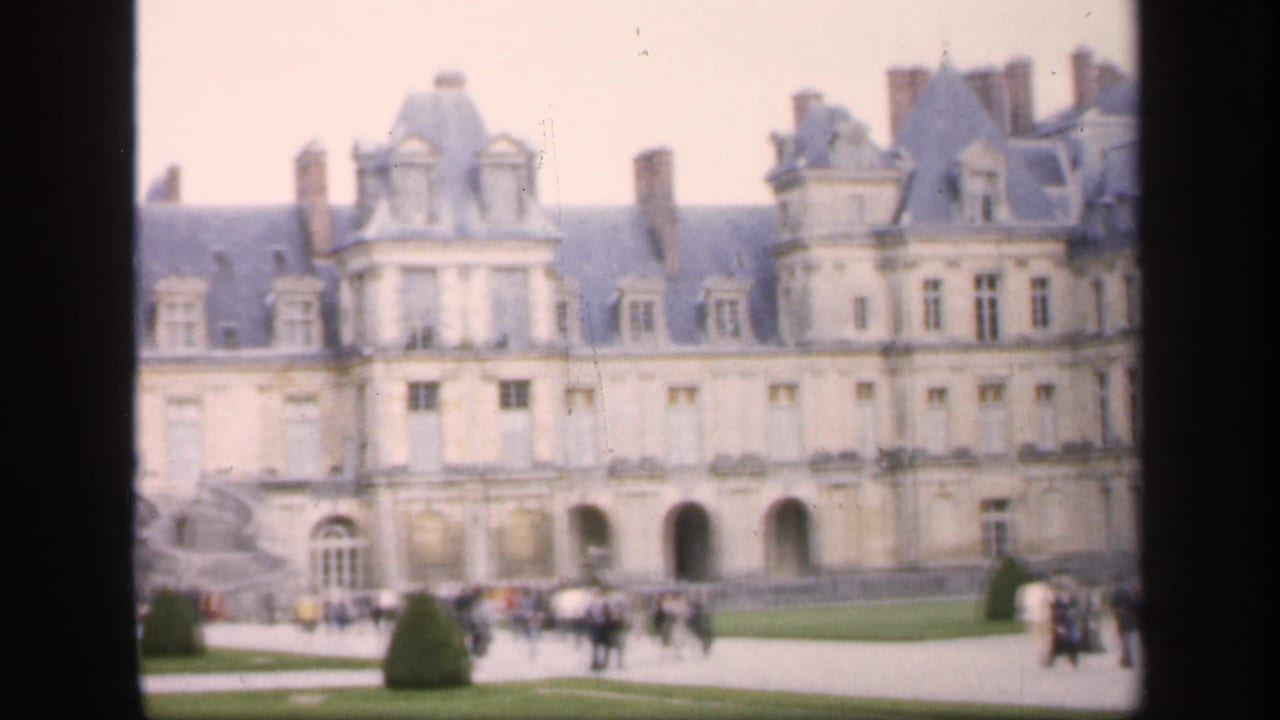 Visitors appear in front of the castle-like building and formal lawn, filmed in soft 8mm color in 1949 Ireland.