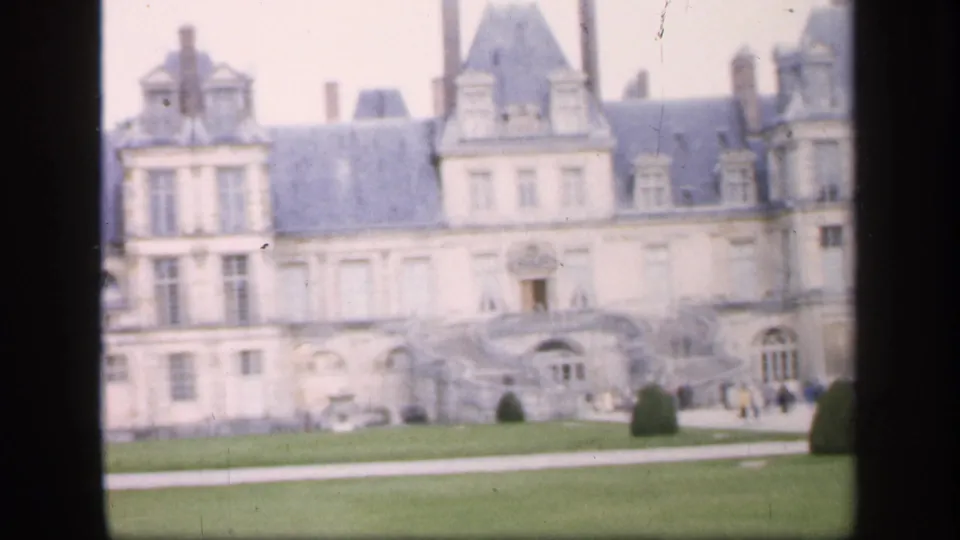 The final frame shows a castle-like wing, formal garden paths, and visitors in distant view on 1949 8mm footage.
