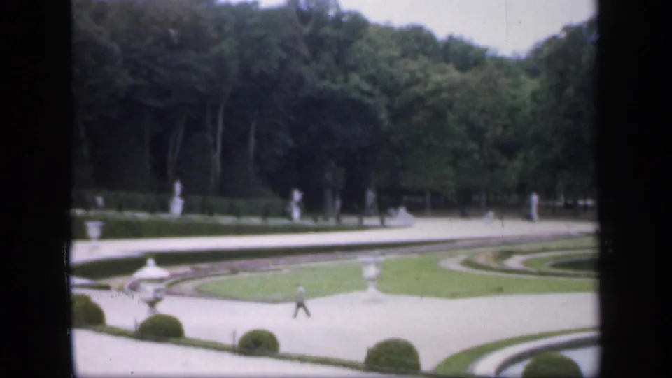 1949 Ireland 8mm frame looking across formal paths, lawns, statues, wooded borders, and a small distant visitor.