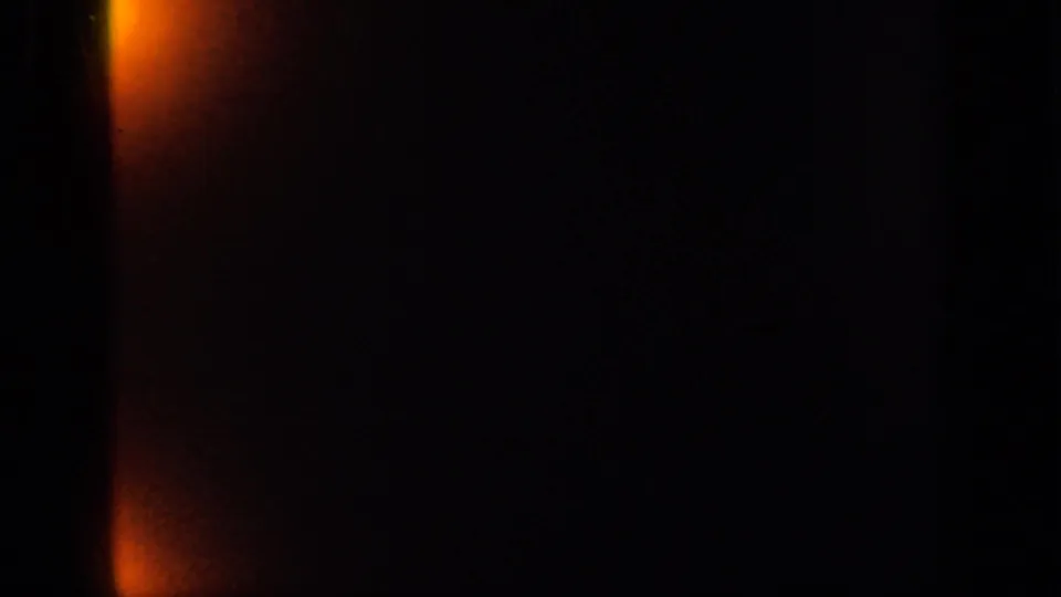 End frame from the 1949 Ireland 8mm clip showing a mostly dark film area with orange light leak and little visible garden detail.