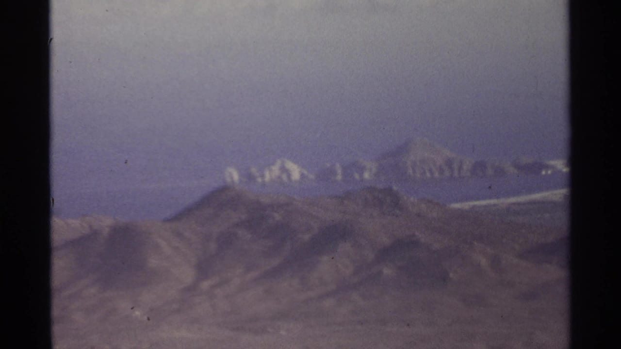 Hazy mountain ridges and arid terrain seen from above through a film frame.