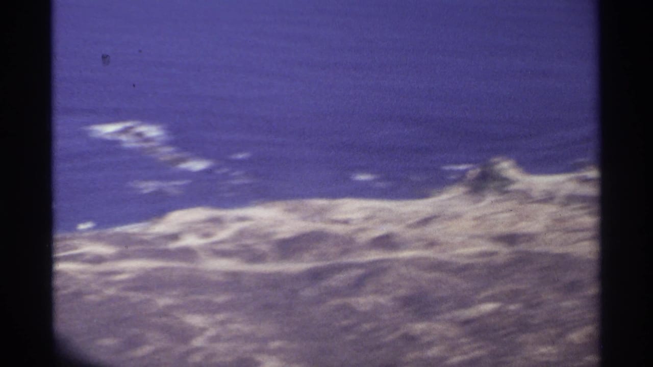 Aerial view of rugged shoreline and ocean divided by airplane window framing.