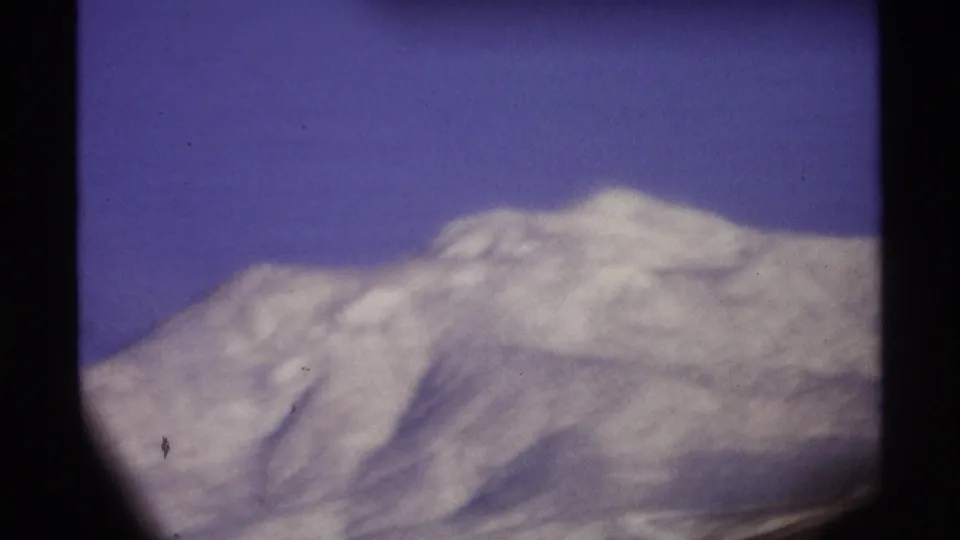 1974 8mm home-movie frame from Cabo San Lucas metadata showing a pale mountain slope seen through dark foreground obstruction.