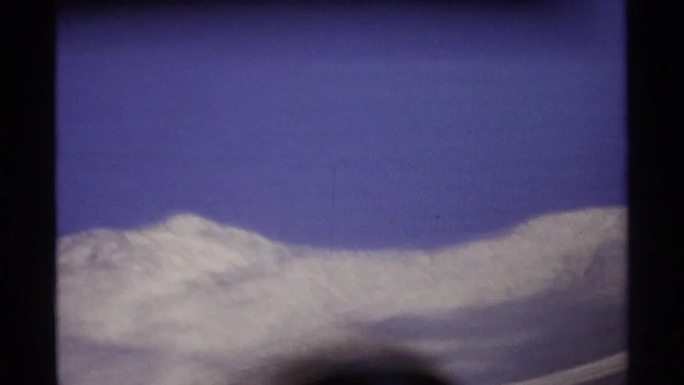 1974 8mm Cabo San Lucas travel frame showing a distant low ridge and sky divided by a dark central foreground bar.
