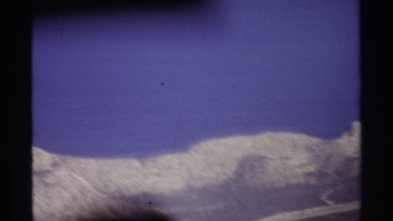 Snow-covered mountain ridge beneath a deep blue sky with dark film borders.