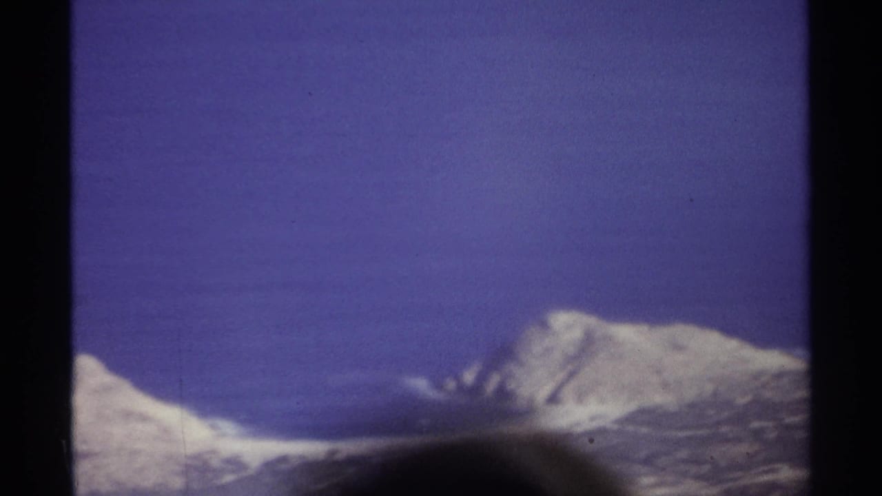 1974 Cabo San Lucas 8mm frame showing deep blue ocean, white surf, pale beach, and rocky shoreline with dark film borders.