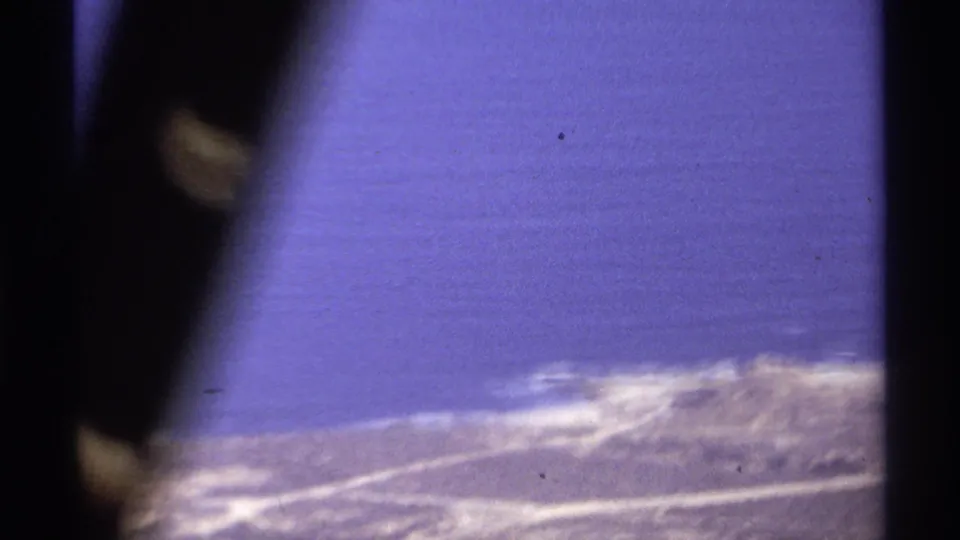 1974 Cabo San Lucas 8mm frame with open blue ocean, pale surf line, distant shore, and dark foreground obstruction.
