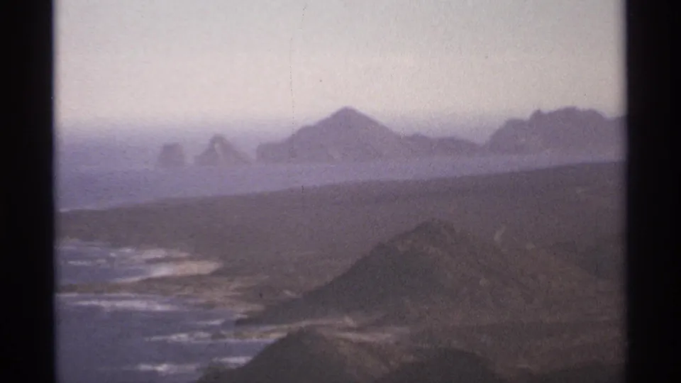 Cabo San Lucas coastal hills and surf appear in soft 1974 8mm footage with distant island-like rock formations.