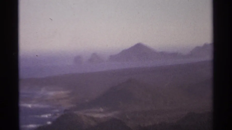 Cabo San Lucas coastal mountains and shoreline appear under a hazy sky in this soft 1970s 8mm frame.