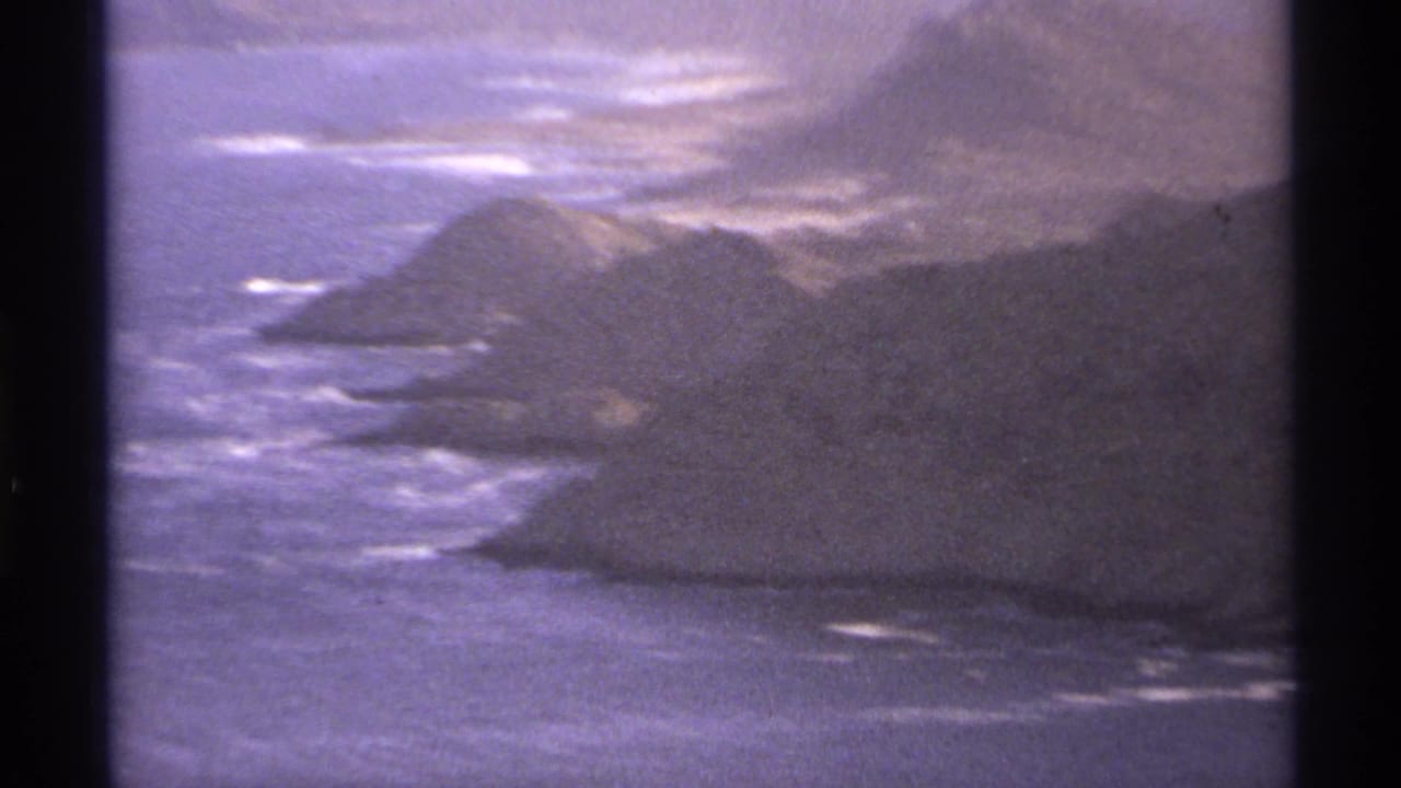 Mountainous rocky shoreline with waves visible near the coast.