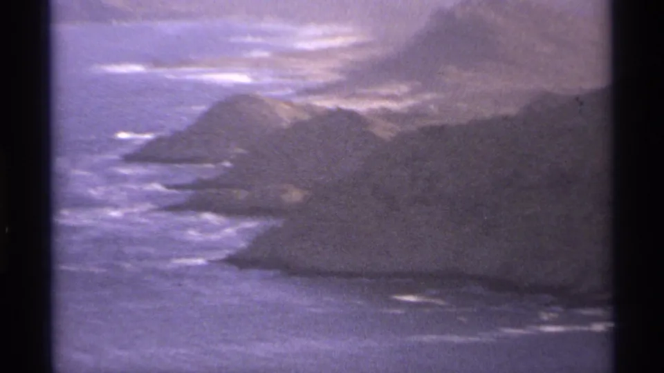 Cabo San Lucas coastal mountains and surf in a purple-tinted 1974 8mm home-movie frame.