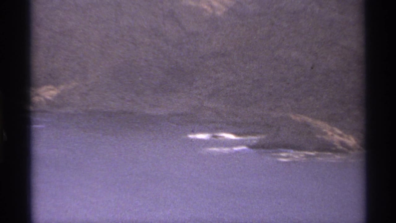 Coastal water and rocky desert hillside seen through dark film-frame borders.