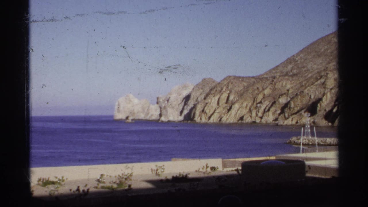 Rocky coastal shore with blue ocean water and a low beach wall.