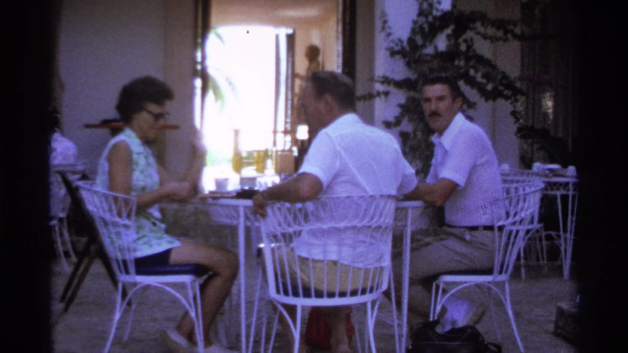 Adults remain seated at the patio table, with one man looking toward the camera.