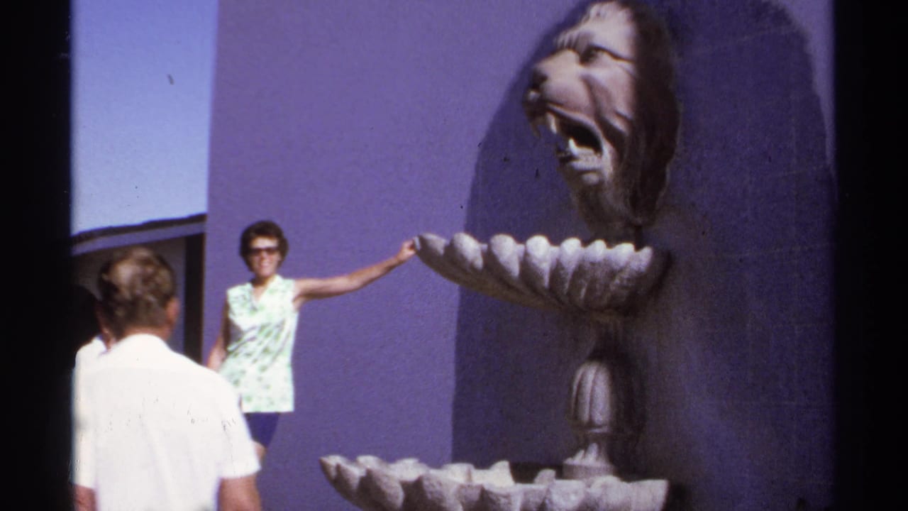 Woman in sunglasses touches a lion-head fountain while a man stands nearby.