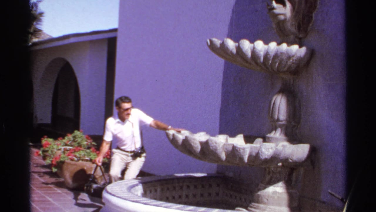 Man reaches toward the scalloped basin of a stone fountain in a courtyard.