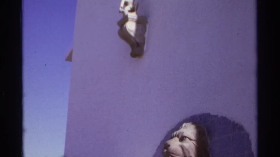 A handheld 1974 Cabo San Lucas shot shows a small wall-mounted decorative figure above the lion sculpture on a purple exterior wall.