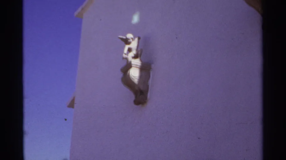 The final frame isolates a small decorative wall figure on a purple Cabo San Lucas exterior, with film grain and color shift visible.