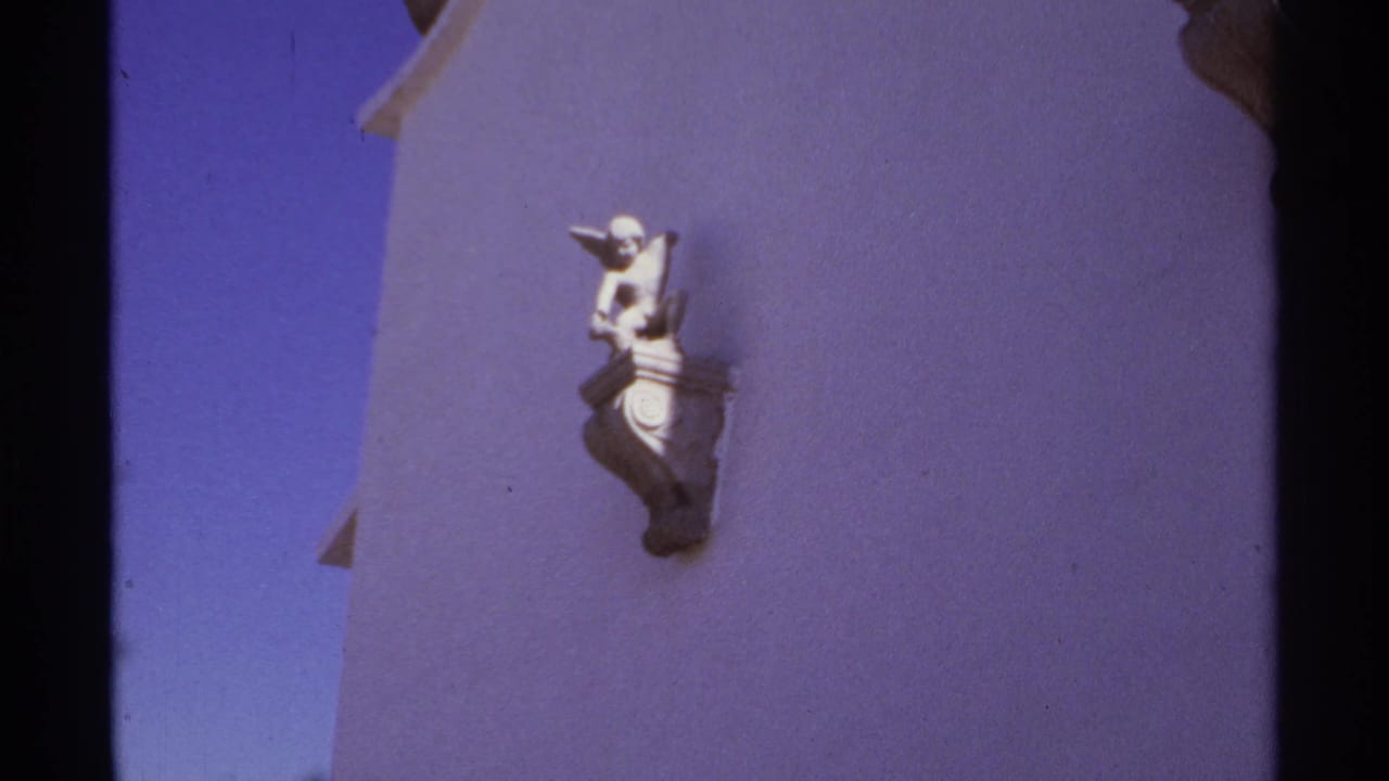 White stucco wall with a small decorative figure in strong sunlight.