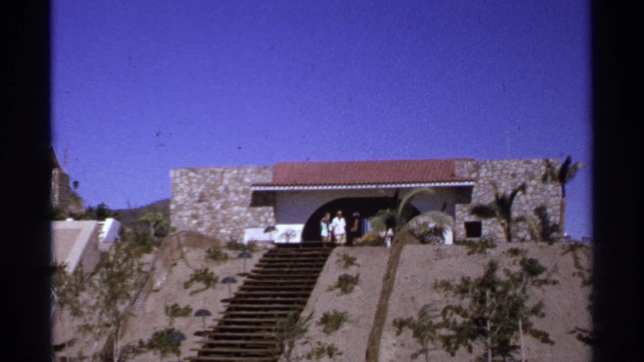 In 1974 Cabo San Lucas home-movie footage, several vacationers appear near the arched entrance of a stone hillside house above a broad staircase.