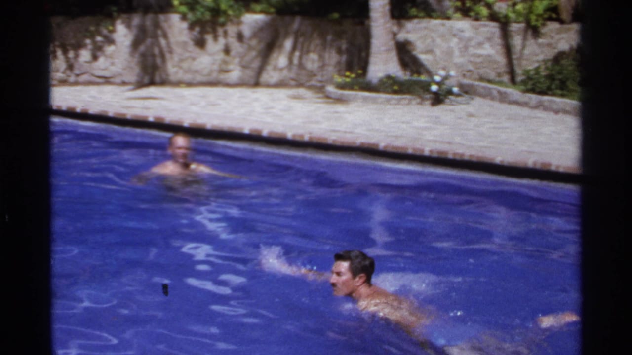 One man swims near the camera while another man is farther back in the pool.
