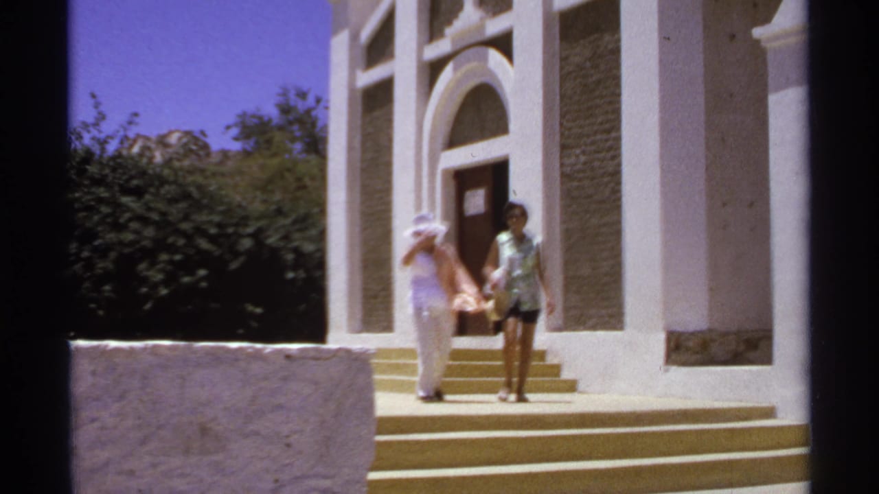 Two women walk down church steps beside a white columned facade.