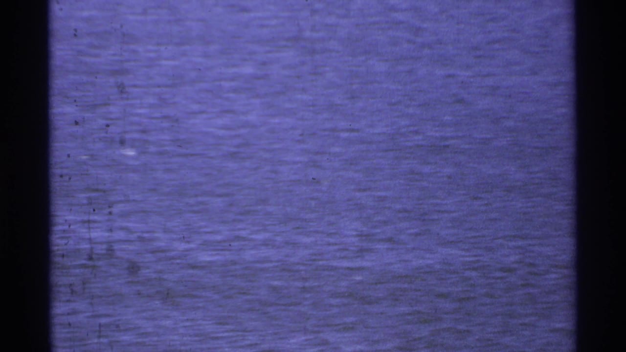 1974 Cabo San Lucas 8mm frame showing rippled ocean water with aged purple-blue color and visible film grain.