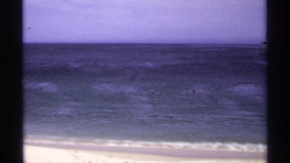 1974 Cabo San Lucas 8mm view of beach, surf, and open ocean with soft grain and faded purple tint.