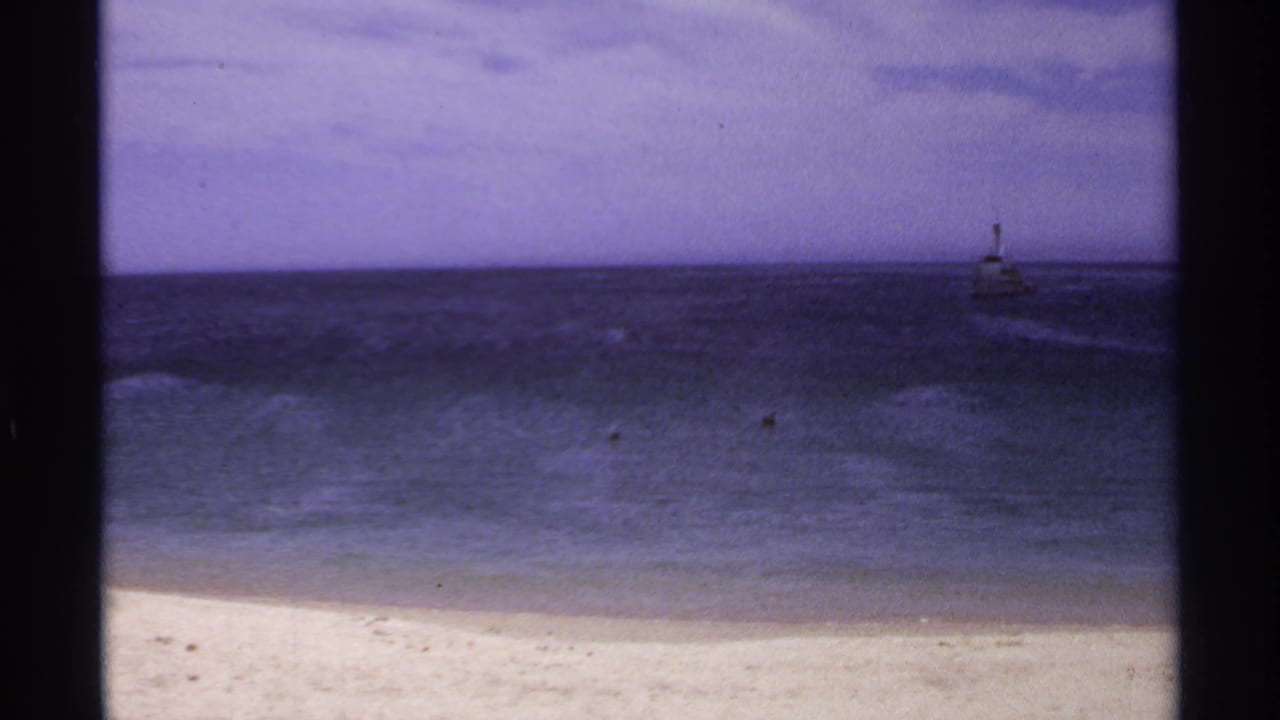 Beach and dark ocean with a small structure near the right horizon.