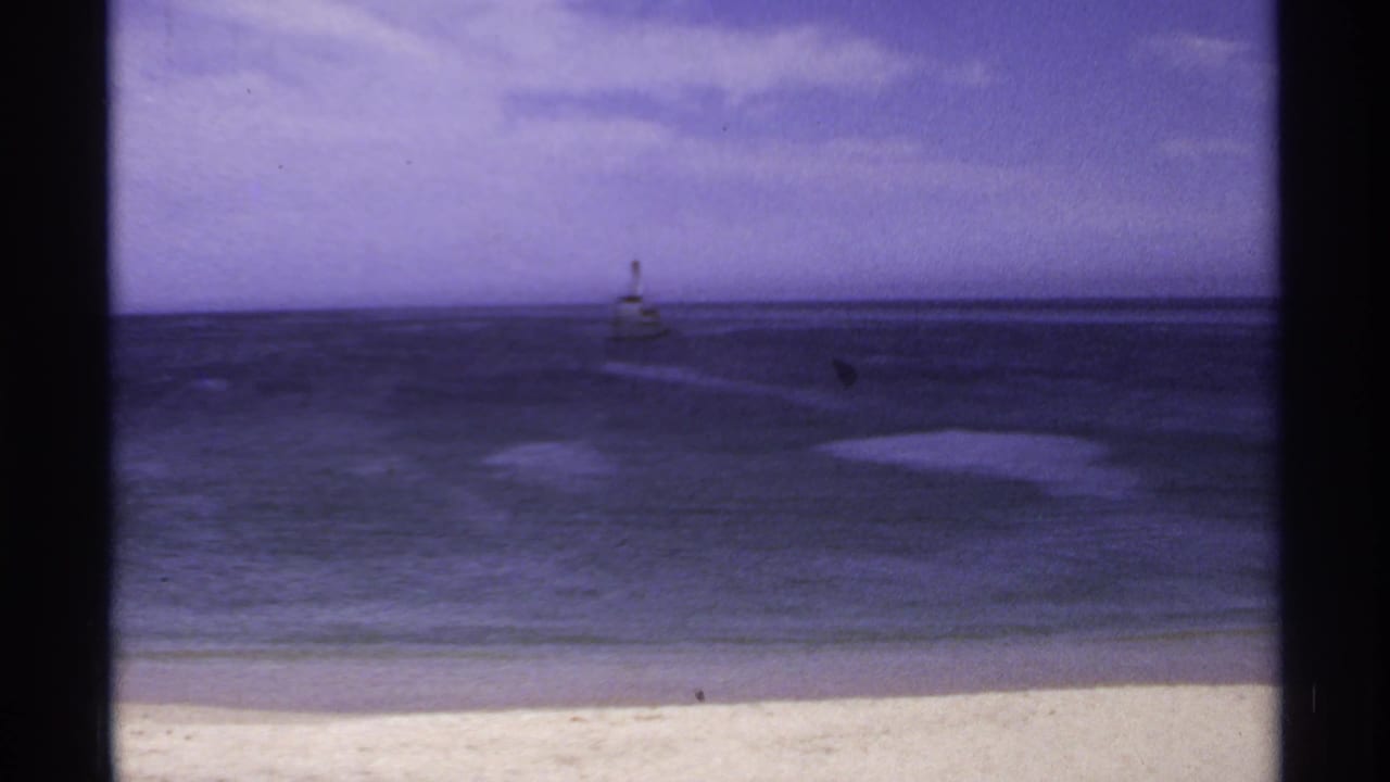 Ocean horizon with a small offshore beacon and pale beach foreground.