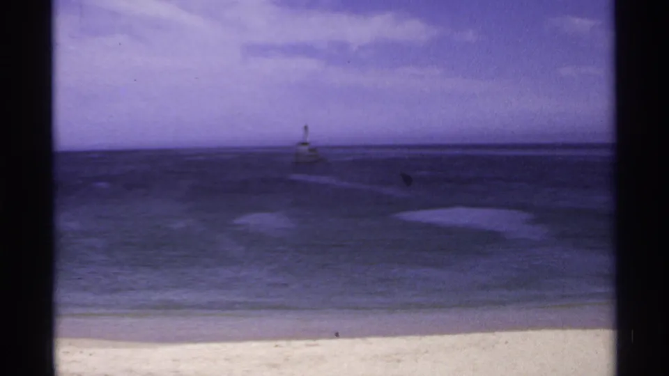 Cabo San Lucas beach and open sea, with a small distant beacon centered beyond the surf.