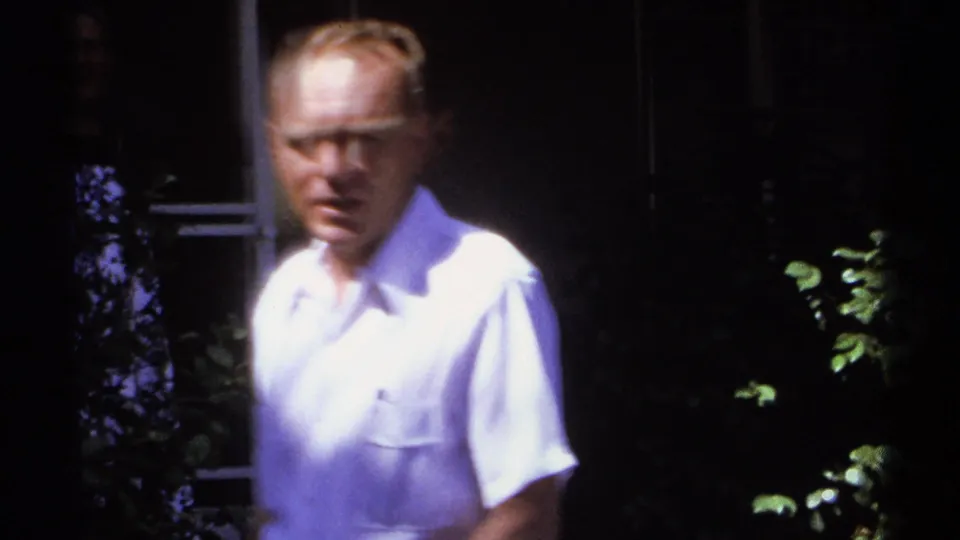 A soft-focus close view captures the man near plants and a shaded exterior wall in the 1974 La Paz home movie.