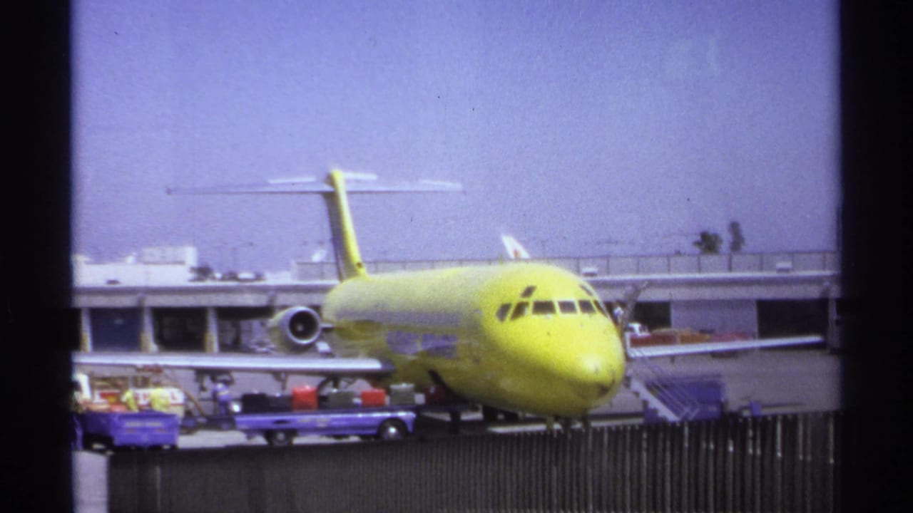 Yellow aircraft parked at the La Paz airport in 1974 while baggage carts and ground activity appear near the nose and wing.