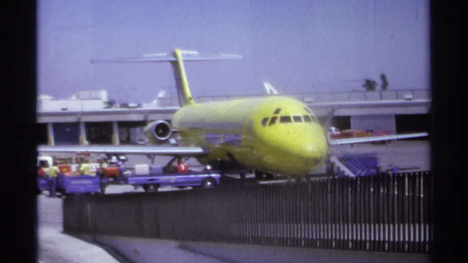 The final 1974 La Paz airport frame holds on the parked lime-green aircraft as luggage handling continues near the terminal.
