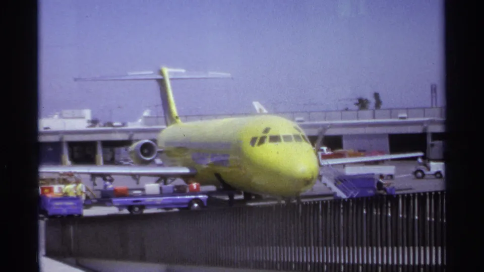 La Paz airport scene from 1974 showing the yellow jet still at the gate, with stairs, ground equipment, and a small service vehicle nearby.