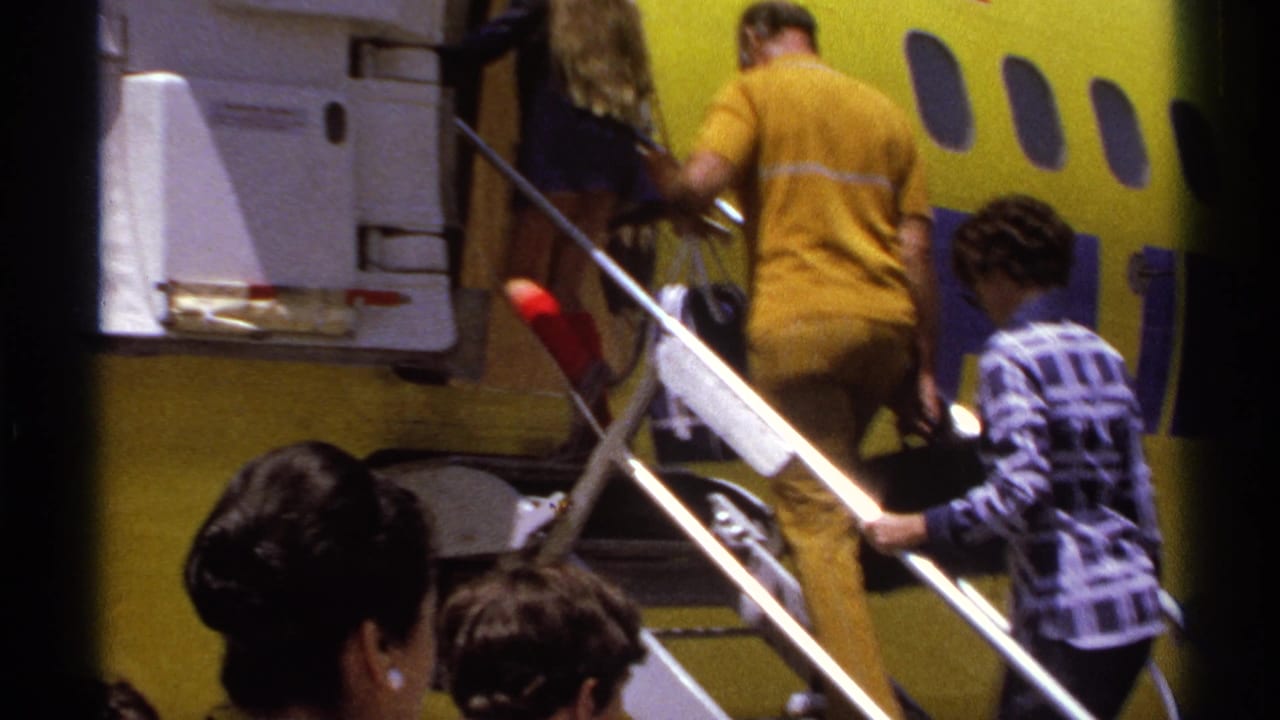 In La Paz, Mexico in 1974, travelers board a yellow commercial airplane using mobile stairs while a crew member stands near the door.